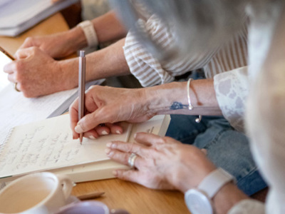 Closeup of hands writing in journals.