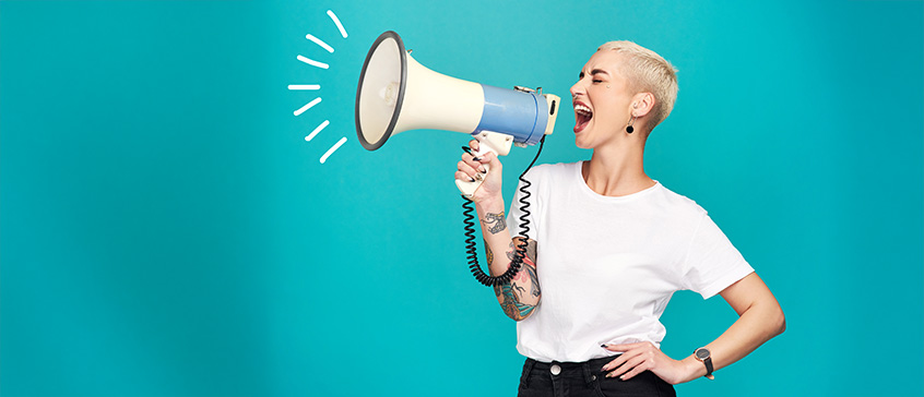 Person holding a large megaphone against a bright teal background, symbolizing communication, outreach, and amplifying messages in public relations.