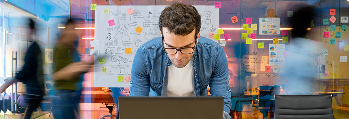 Marketing office worker at laptop in a busy modern office