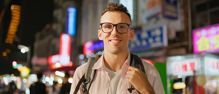 Caucasian man is visiting the Chinese night market in the evening and smiling at you