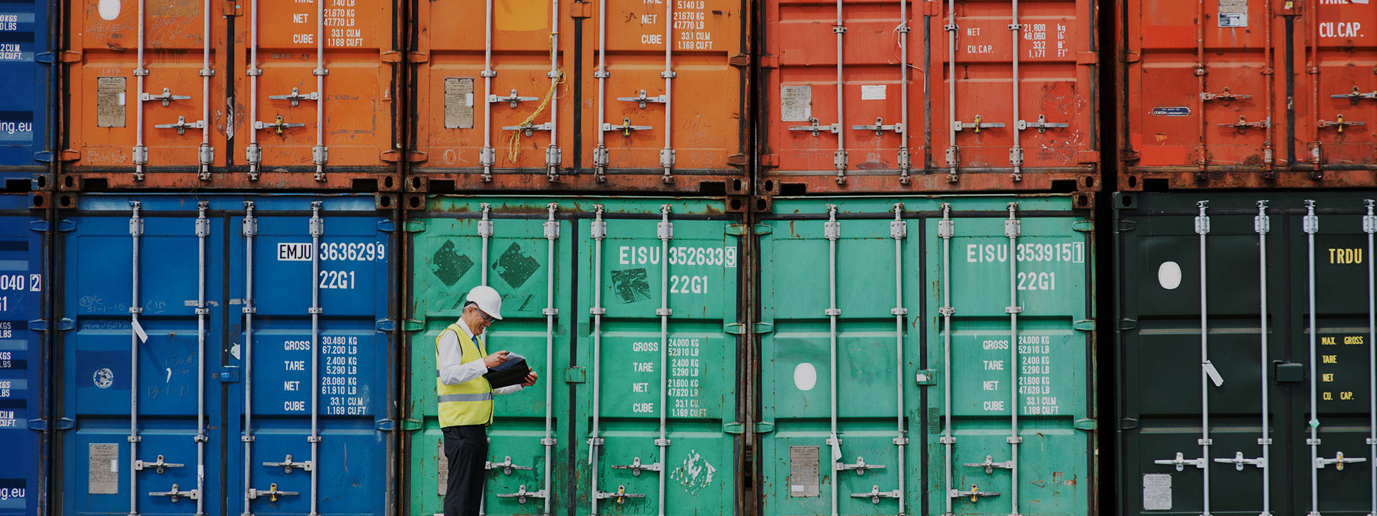 worker taking notes in front of shipping containers