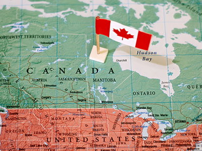 A map of North America focusing on Canada with a Canadian flag placed in the center of Canada.