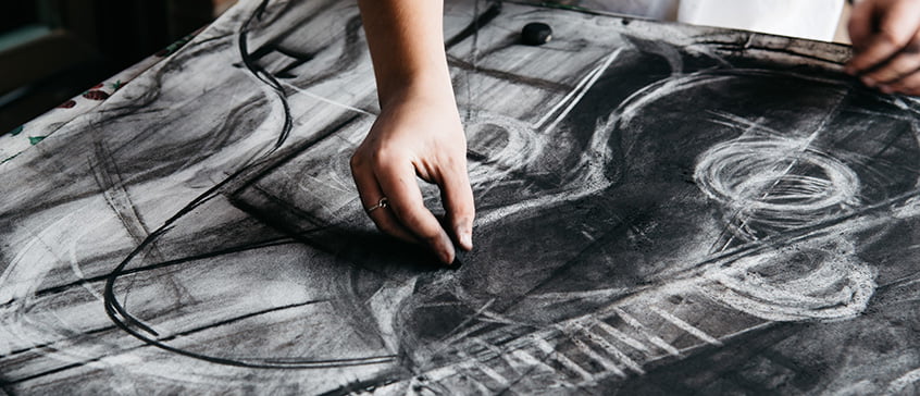 Hand drawing with charcoal on large paper covered in expressive black and white sketches and circular forms, demonstrating the emotional depth and technical range of monochromatic drawing
