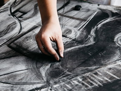 Hand drawing with charcoal on large paper covered in expressive black and white sketches and circular forms, demonstrating the emotional depth and technical range of monochromatic drawing