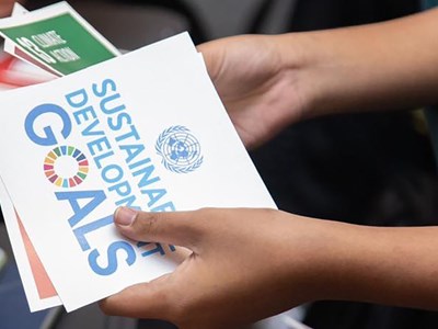 Hands holding workshop cards that read Sustainable development goals.