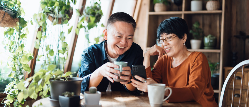 Two people looking at a phone over coffee.