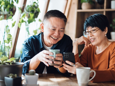 Two people looking at a phone over coffee.