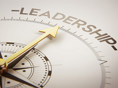 Golden compass with arrow pointing toward the word LEADERSHIP on a curved measurement scale, symbolizing direction and guidance in leadership development