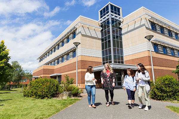 Photo of students walking outside the Continuing Studies building on a summer day