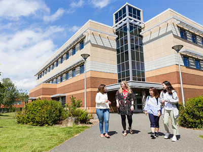 International students walking outside the entrance of the Continuing Studies build on the UVic campus.