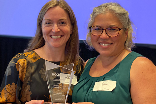 Two women smiling and holding an award at the BCCIE International Education Awards ceremony.