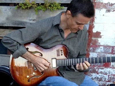 Photo of Patrick Walters strumming his guitar. 