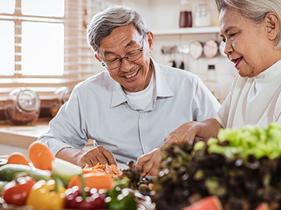 Senior woman and man prepping a large assortment of fresh vegetables in kitchen