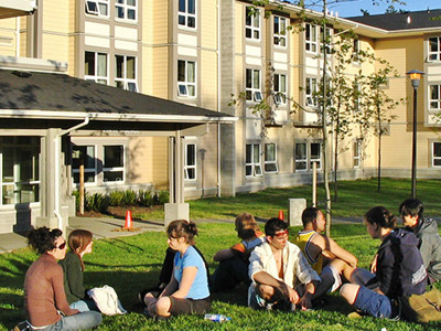 Students sitting on grass eating picnic in front of UVic dorm.