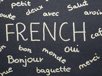 A chalk board with FRENCH written and a number of common French words surrounding it.