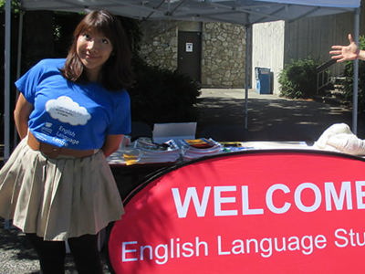 2 English Language students with a sign saying welcome.