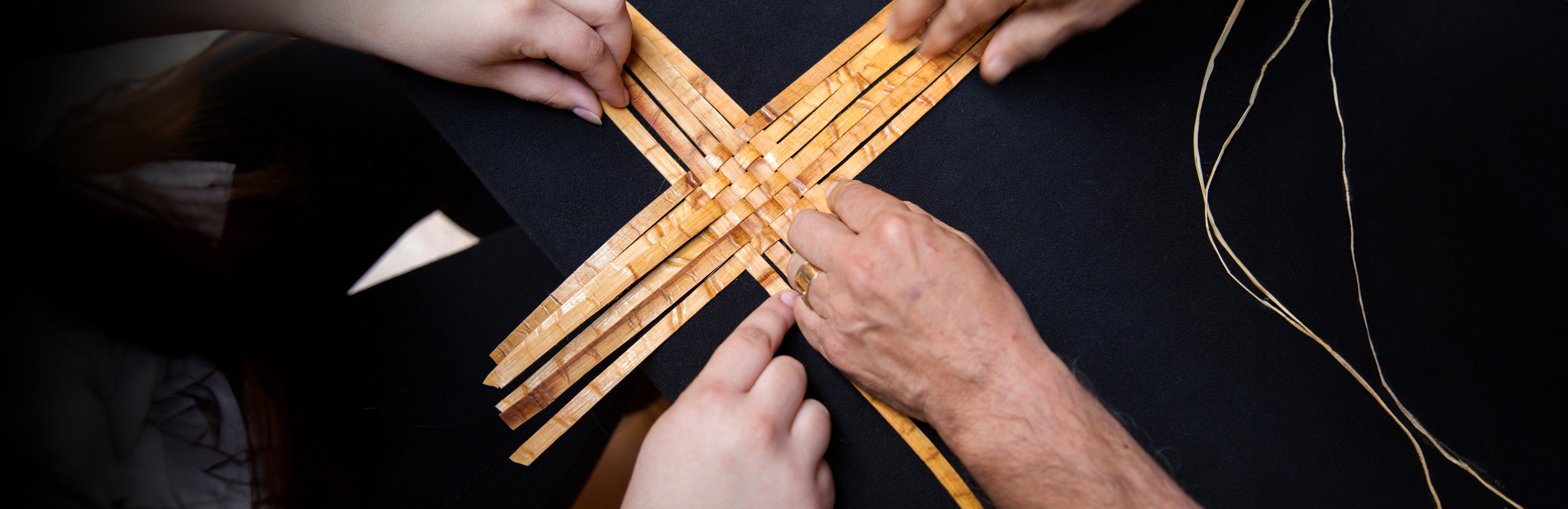 Close up on hands working on a tree bark weaving. 