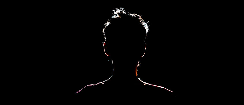 Photo of man in shadow with silhouette outlined by light. 