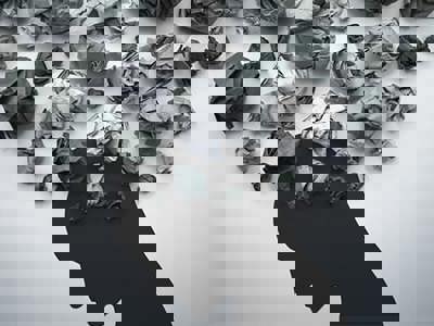Illustration with crumpled up balls of paper over a silhouette of a person.