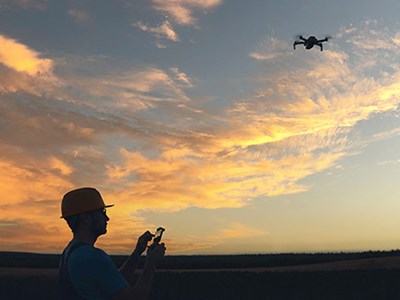 Silhouette of drone operator against sunset. 