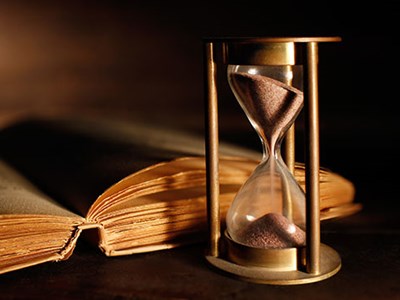 Photo of hourglass and old book.