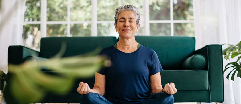 Woman meditating in lotus position at home