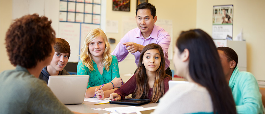  High School Students With Teacher In Class Using Laptops 