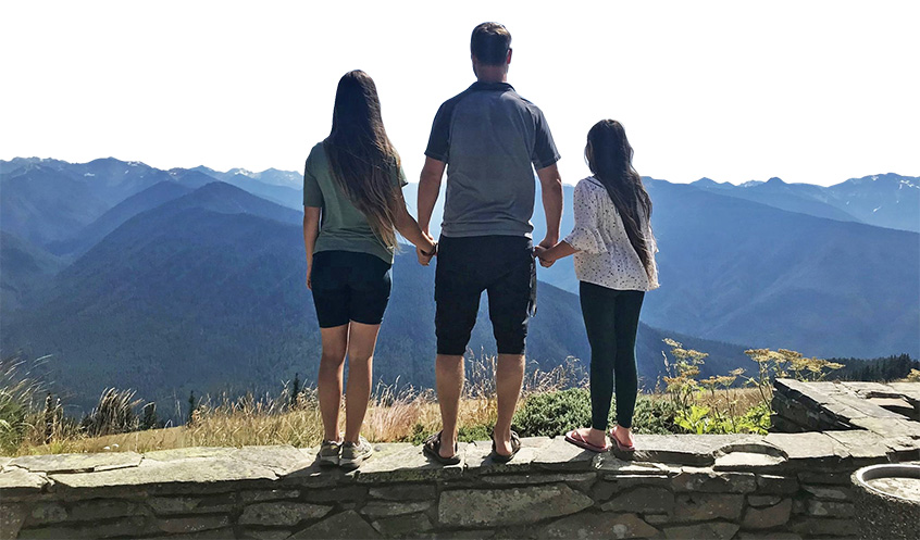 Photo of Philippe and his two daughters in front of a BC mountain range.