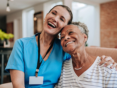Nurse and senior sitting closely on couch and smiling